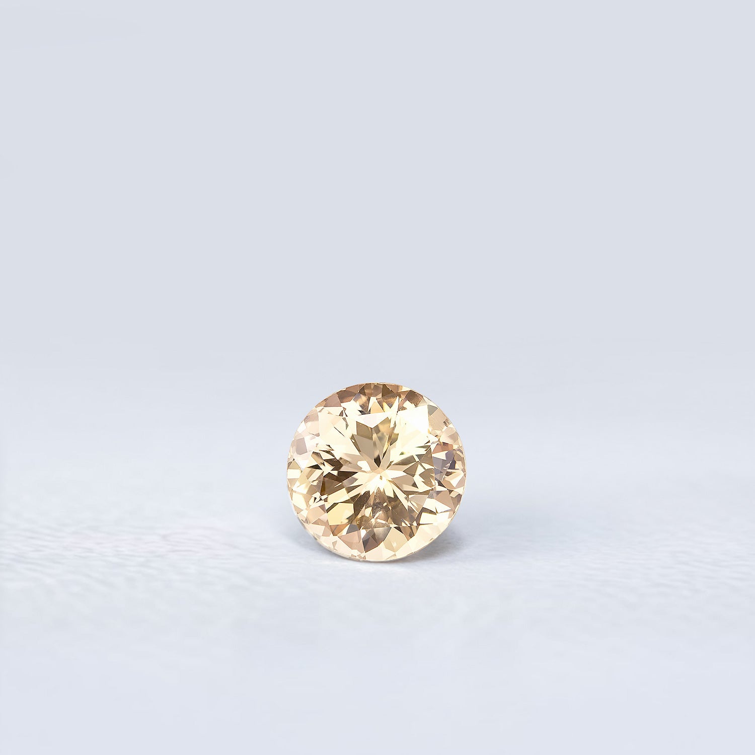 Saphir pêche naturel non chauffé rond facetté de 1.28 carat, aux nuances brun-jaune légères, originaire du Sri Lanka