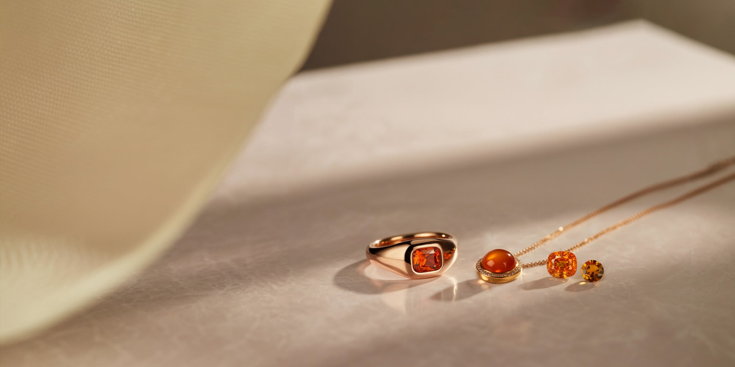 Bague et pendentif contemporains sertis de pierres fines orange, accompagnés de gemmes taillées.