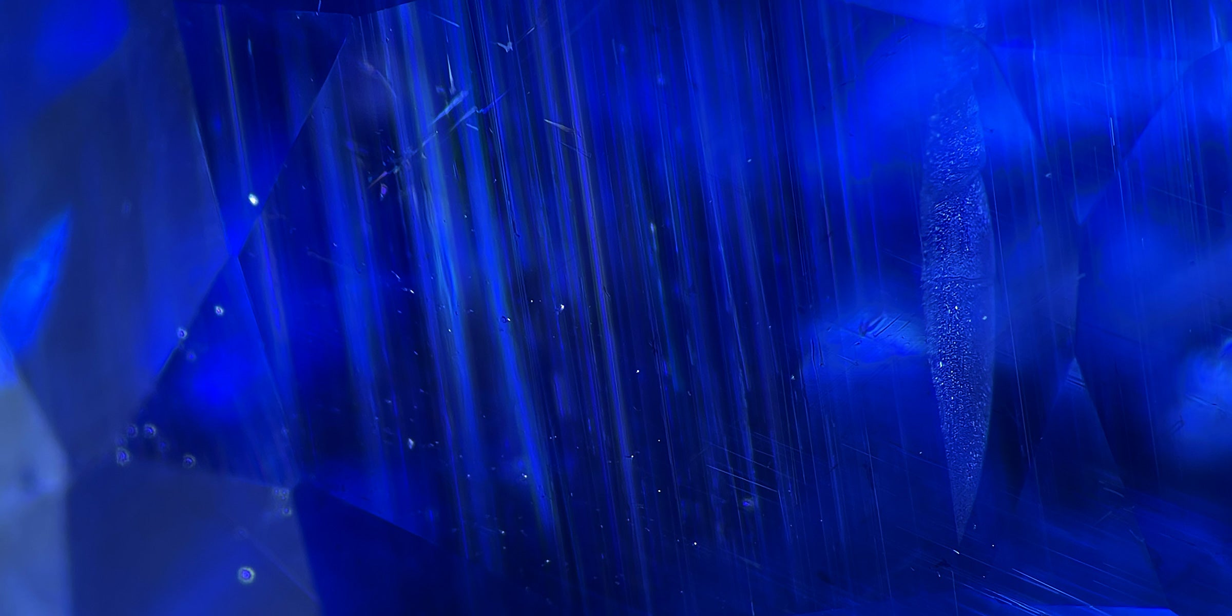 Inclusions observées au microscope dans une gemme bleue, révélant l’authenticité de la pierre.