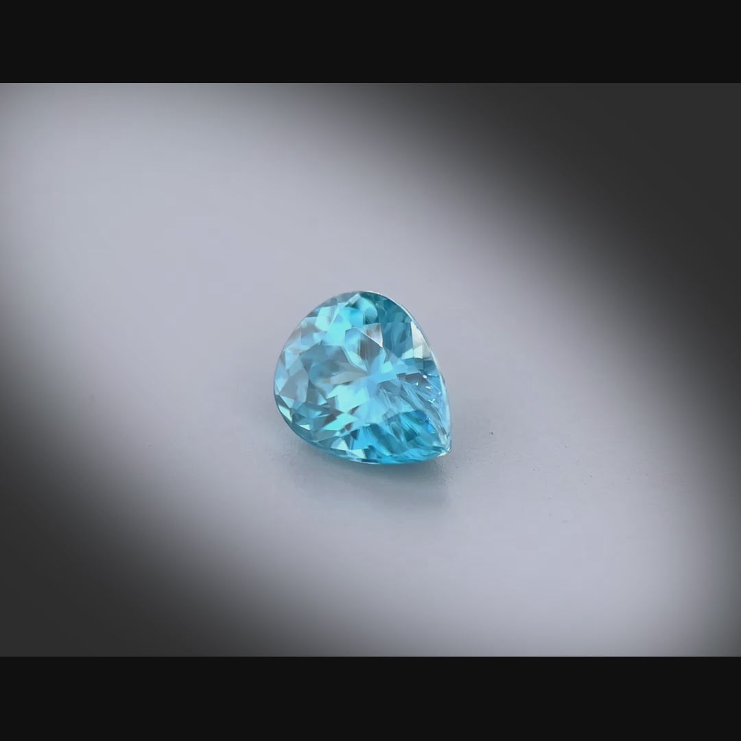 Vidéo d’un zircon bleu naturel poire de 1.89 ct, facetté, de couleur cyan-bleuté soutenu, originaire du Cambodge, tournant à 360 degrés sur fond gris clair