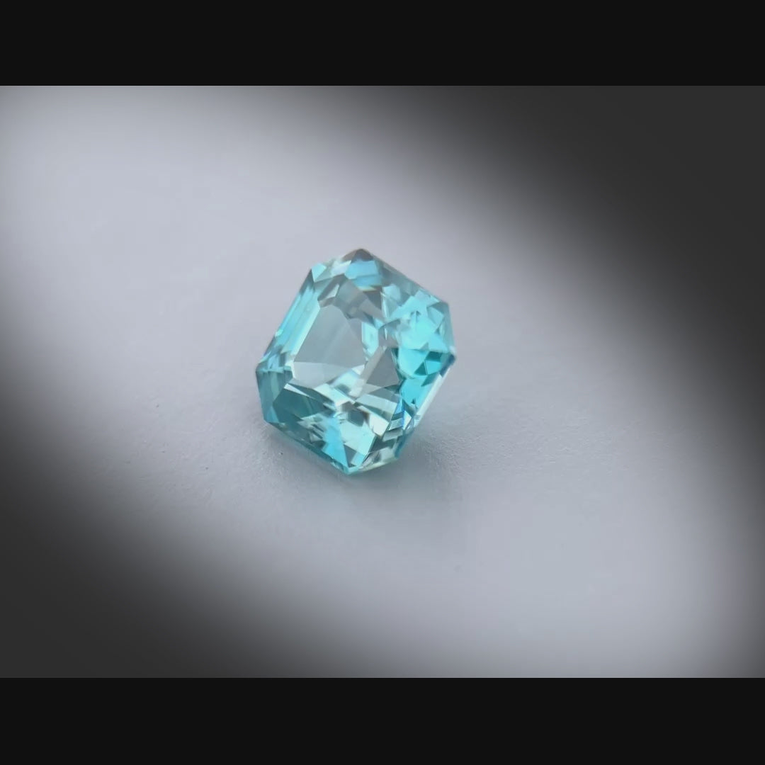Vidéo d’un zircon bleu cyan naturel de 2.99 ct, taillé en carré à pans coupés, tournant à 360° sur fond gris clair