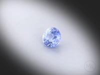 Vidéo d’un saphir bleu naturel rond facetté de 1.21 ct, originaire de Madagascar, de couleur bleu léger, pierre précieuse tournant sur un fond gris clair.