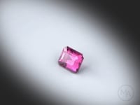 Vidéo d’un grenat violet naturel rectangle à pans coupés facetté de 1.07 ct, de couleur violet intense, tournant sur un fond gris clair.