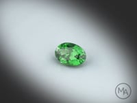 Vidéo d’un Grenat Tsavorite naturel non traité, ovale facetté de 1.04 ct, de couleur vert intense, tournant sur un fond gris clair.