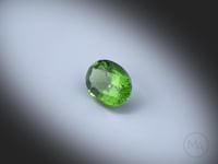 Vidéo d’une tourmaline verte naturelle non traitée ovale facettée de 1.27 ct, de couleur vert profond, tournant sur un fond gris clair.