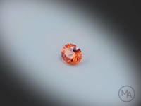 Grenat spessartite naturel ovale facetté de 1.13 carat, de couleur orange intense et très légèrement inclus. Vidéo en rotation sur fond gris clair. Provenance Tanzanie.