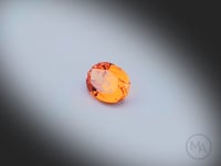 Vidéo d’un grenat spessartite naturel ovale facetté de 1.34 ct, originaire du Nigéria, de couleur orange soutenu, tournant degrés sur un fond gris clair. Aucun traitement.