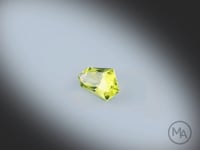 Vidéo d’un péridot naturel facetté de forme abstraite de 0.90 ct, originaire du Myanmar, de couleur vert-jaune prononcé, tournant sur un fond gris clair.