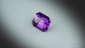 Vidéo d’un grenat violet naturel rectangle à pans coupés facetté de 1.41 ct, originaire du Mozambique, de couleur violet intense, rotation sur un fond gris clair.