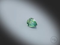 Vidéo d’un saphir bicolore naturel poire facetté de 0.88 ct, originaire d’Australie, présentant une association naturelle de jaune et de bleu-vert, gemme en rotation sur un fond gris clair.
