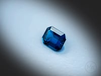 Vidéo d’une topaze bleue naturelle London Blue rectangle à pans coupés facettée de 2.64 ct, originaire du Brésil, de couleur cyan-bleuté profond, rotation sur un fond gris clair.