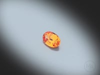 Vidéo d’un Grenat Spessartite naturel ovale facetté de 0.68 ct, originaire du Nigéria, de couleur orange soutenu, pierre précieuse tournant sur un fond gris clair.
