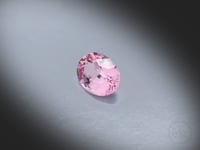 Vidéo d’un Grenat Malaya naturel ovale facetté de 1.79 ct, originaire de Tanzanie, de couleur rose-brun léger, pierre fine rare tournant sur un fond gris clair.