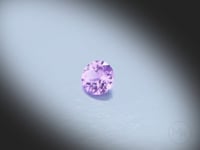 Vidéo d’un Saphir violet naturel rond 5mm facetté de 0.53 ct, originaire d’Ilakaka à Madagascar, de couleur violet-rosé prononcé, pierre précieuse tournant sur un fond gris clair.