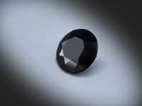 Vidéo d’un Spinelle noir naturel rond facetté de 13.40 ct, originaire de Thaïlande, de couleur noir sombre, pierre opaque tournant sur un fond gris clair.