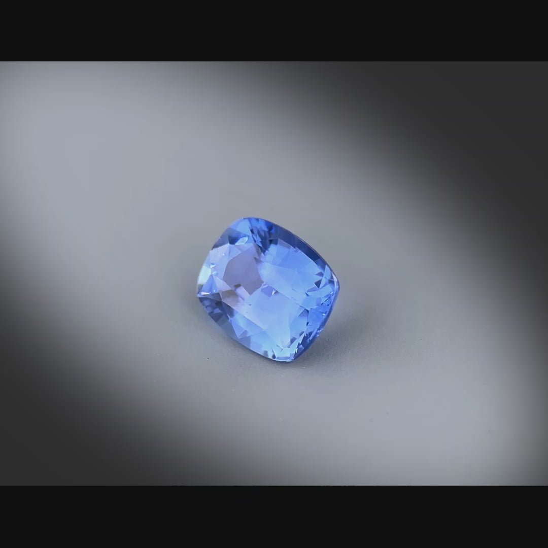 Vidéo d’un saphir bleu naturel non chauffé coussin rectangle de 1.57ct, originaire du Sri Lanka, de couleur bleue soutenue, tournant à 360 degrés sur un fond gris clair.