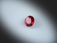 Grenat Rouge naturel de 1.56 ct, originaire de Madagascar, taillé en rond et facetté, avec une couleur rouge profond, présenté en rotation sur fond gris clair.