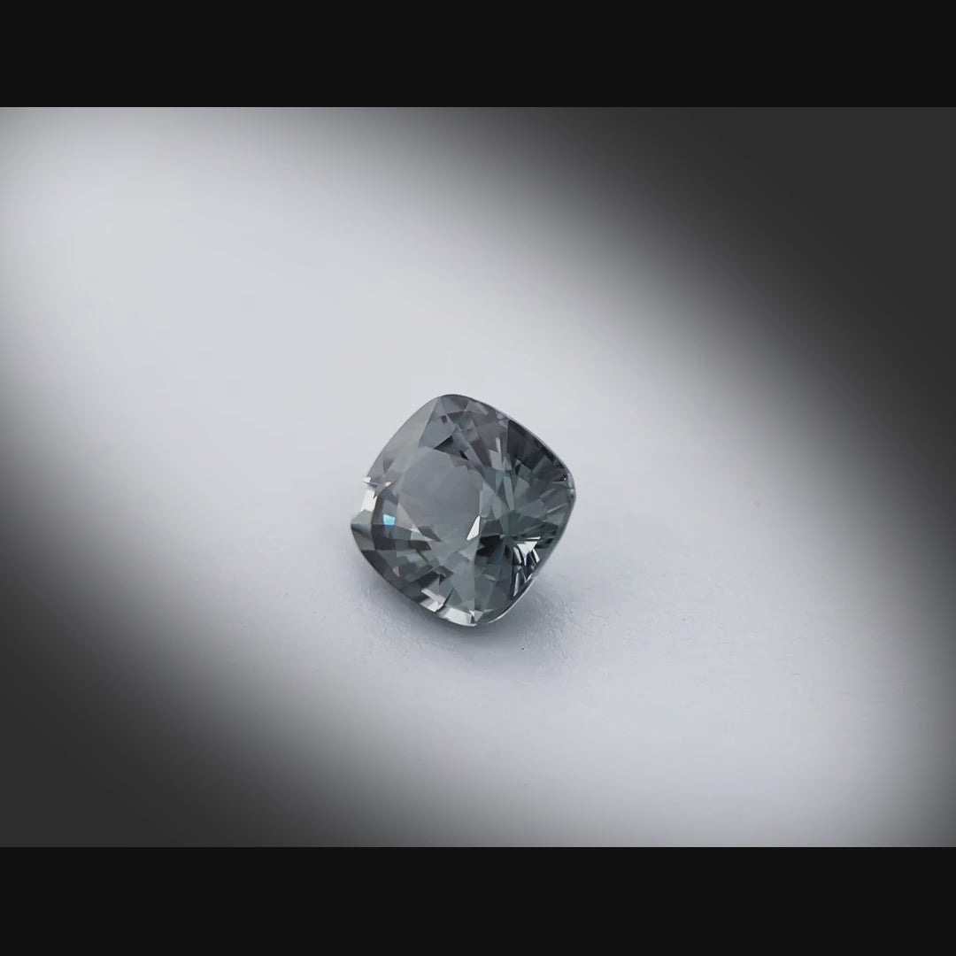 Vidéo d’un spinelle gris naturel coussin facetté de 1.36 ct, originaire du Myanmar, de couleur gris soutenu, tournant à 360 degrés sur fond gris clair