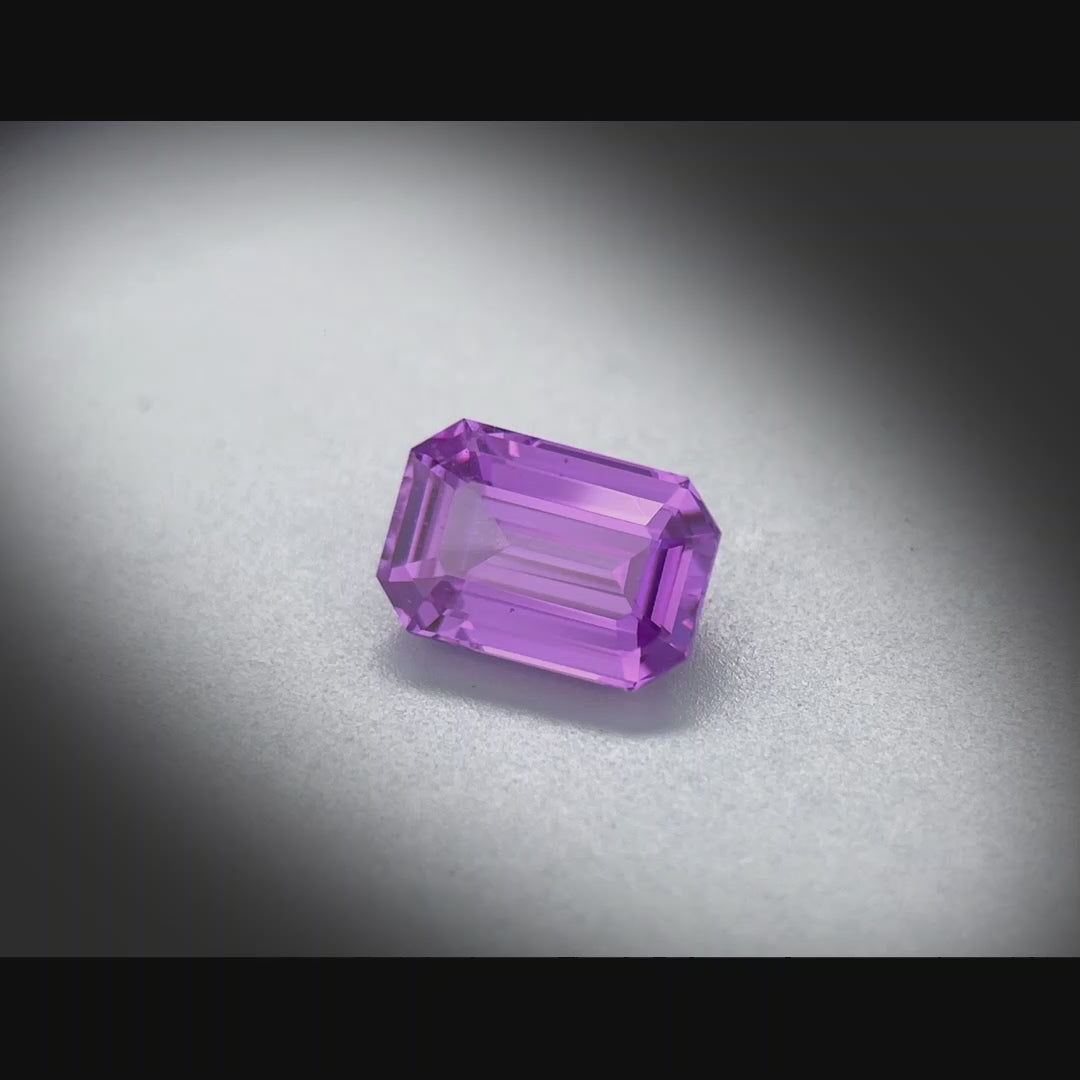 Vidéo d’un saphir violet naturel non chauffé rectangle à pans coupés de 1.67 ct, originaire de Madagascar, de couleur violet intense, tournant à 360 degrés sur un fond gris clair