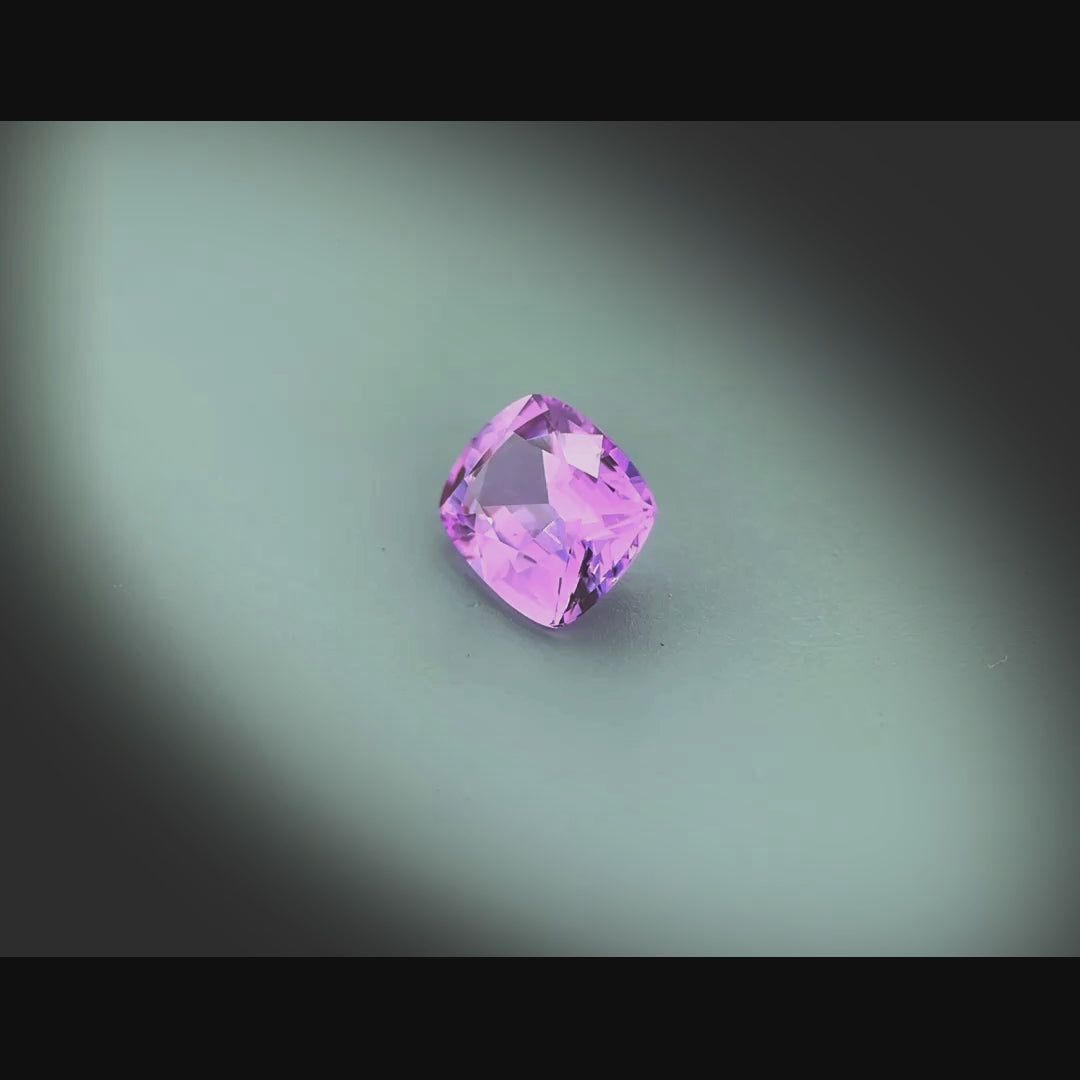 Vidéo d’un saphir rose-violet d'une grande pureté, facetté en coussin rectangle de 1.04 ct, tournant sur fond gris clair.