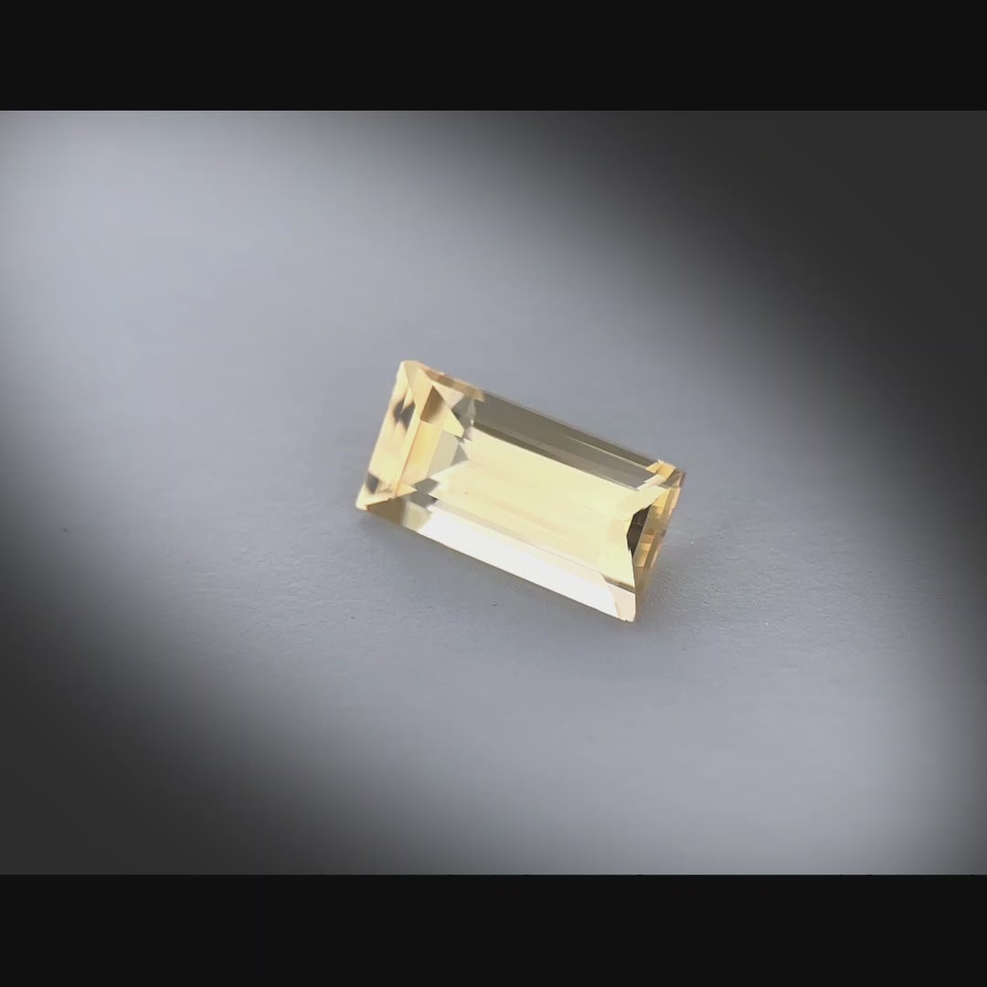 Vidéo d’un saphir jaune naturel non chauffé taille baguette de 1.30 ct, originaire de Madagascar, de couleur jaune-doré léger, tournant à 360 degrés sur un fond gris clair