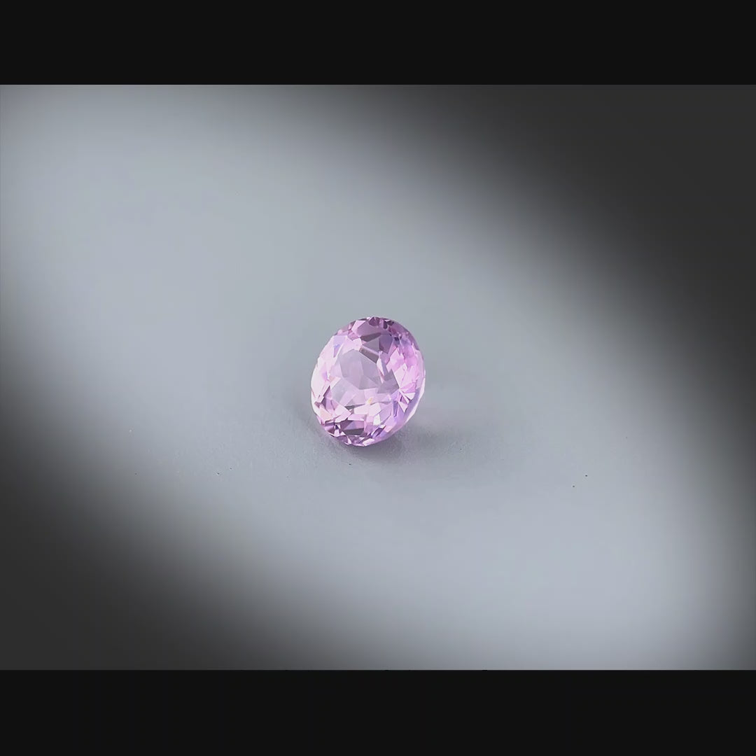 Vidéo d’un saphir rose-violet naturel rond de 0.95 ct, chauffé, originaire de Madagascar, tournant à 360 degrés sur fond gris clair