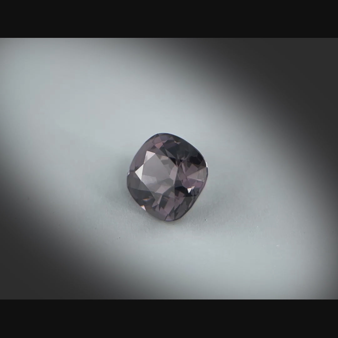 Vidéo d’un spinelle naturel gris-violet sombre coussin rectangulaire de 1.60 ct, facetté et sans inclusion visible, originaire du Myanmar, tournant à 360 degrés sur fond gris clair.