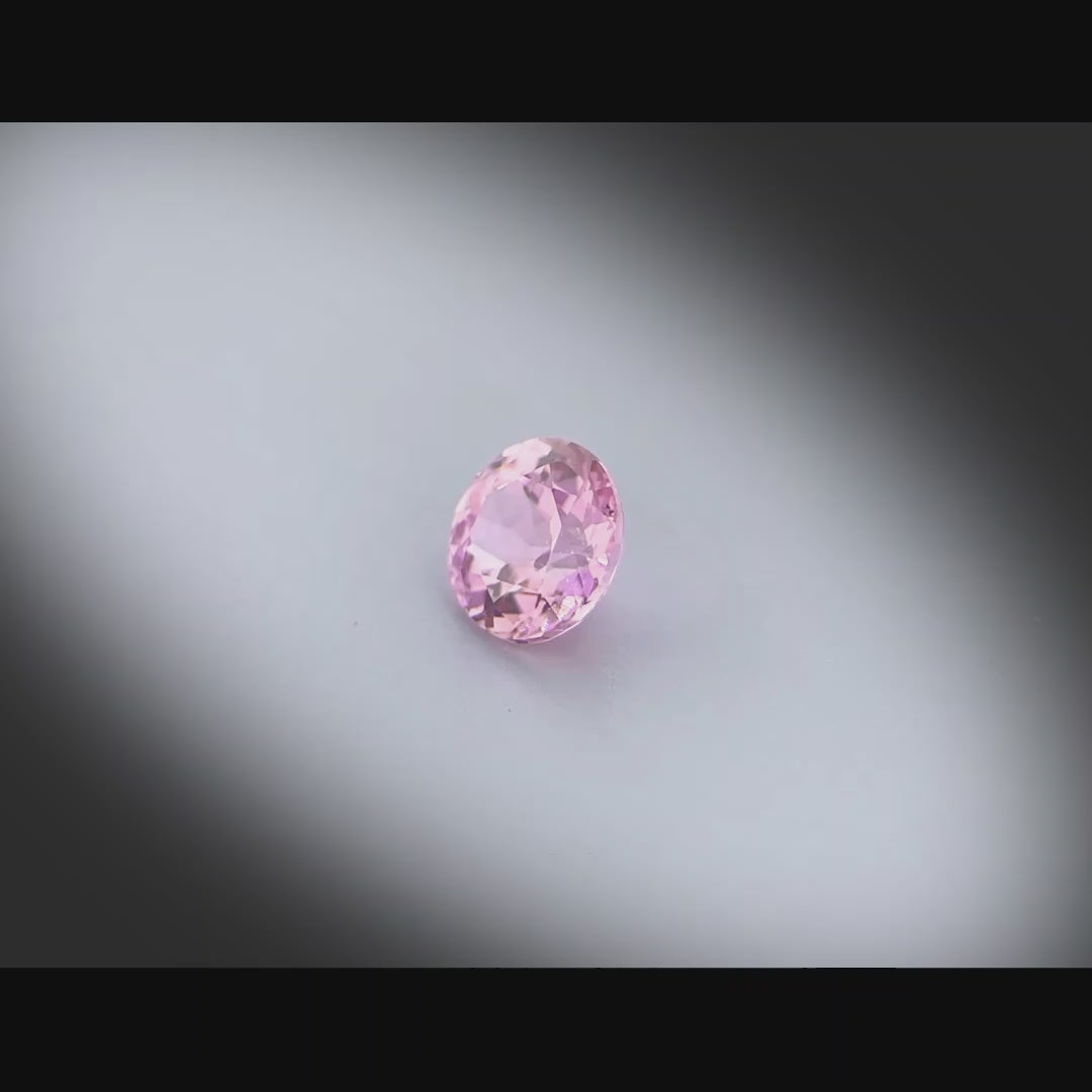 Vidéo d’un saphir rose-violet naturel rond de 0.62 ct, non chauffé, originaire de Madagascar, tournant à 360 degrés sur fond gris clair
