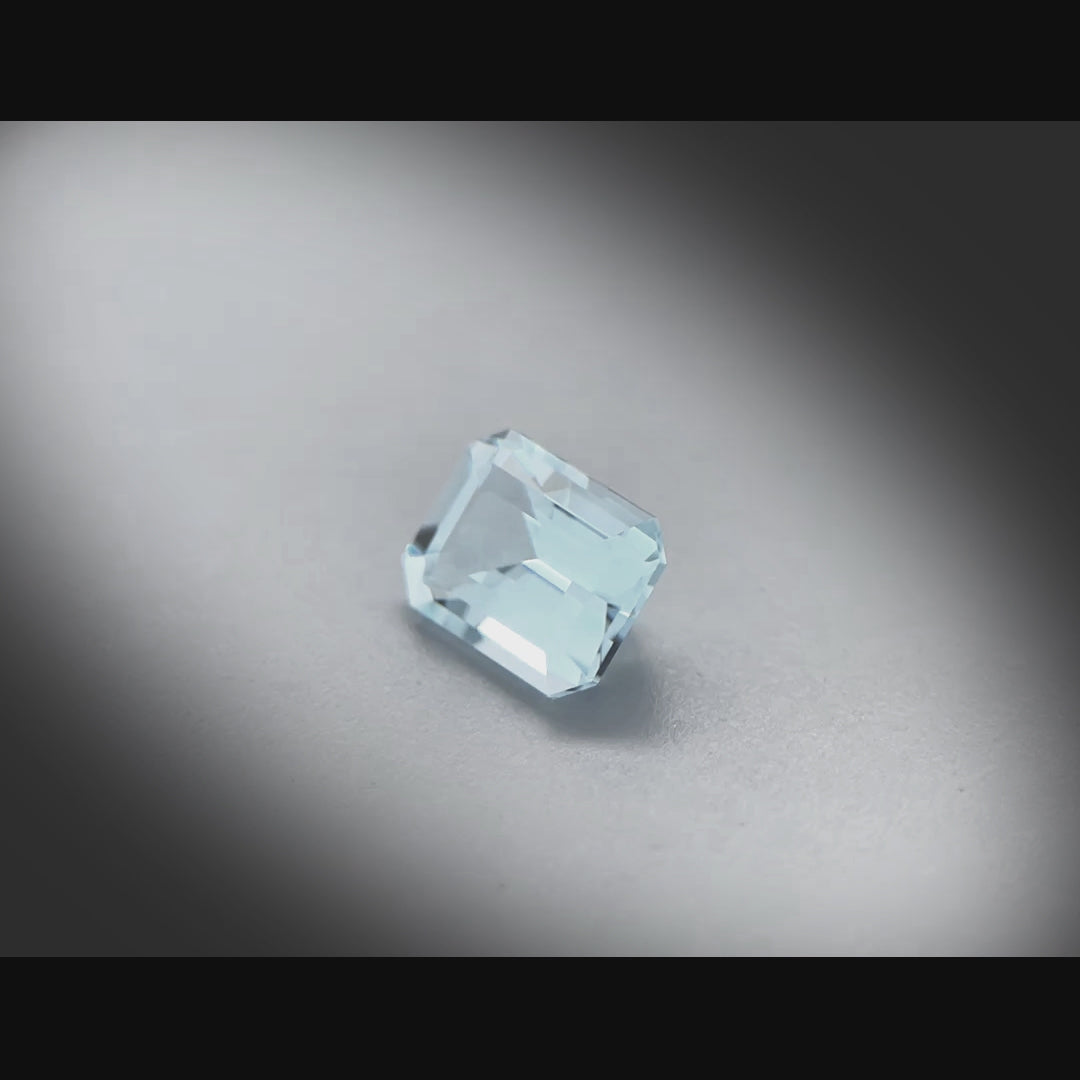 Vidéo d’une topaze bleue facettée 2,77ct, taille rectangle à pans coupés, couleur cyan-bleuté très légère, origine Brésil