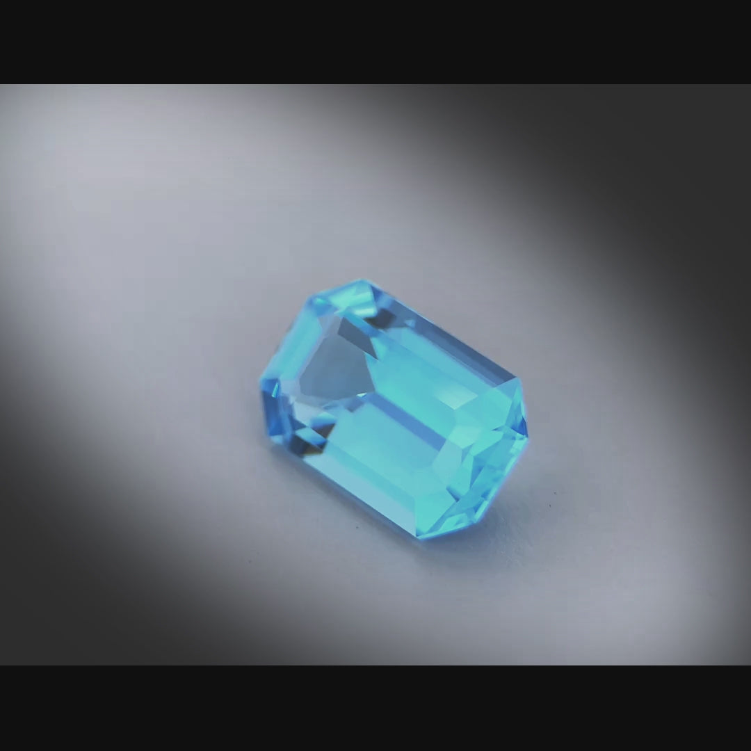 Vidéo d’une topaze bleue rectangle facettée 6,62ct, teinte cyan-bleuté intense, pureté sans inclusion, origine Brésil