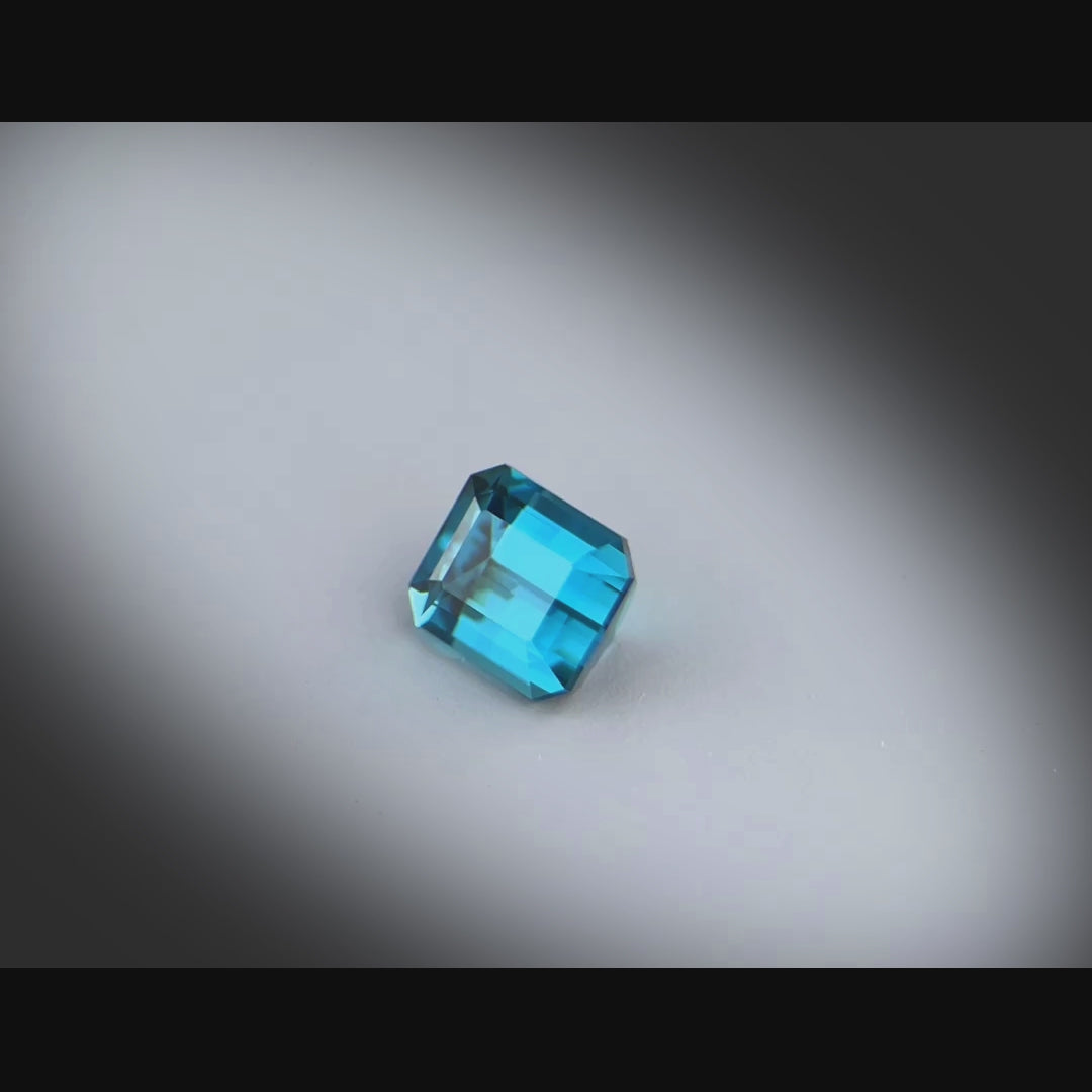 Vidéo d’une tourmaline bleue naturelle 1,25ct, taille rectangle à pans coupés, facettée, couleur cyan-bleuté profond, Brésil