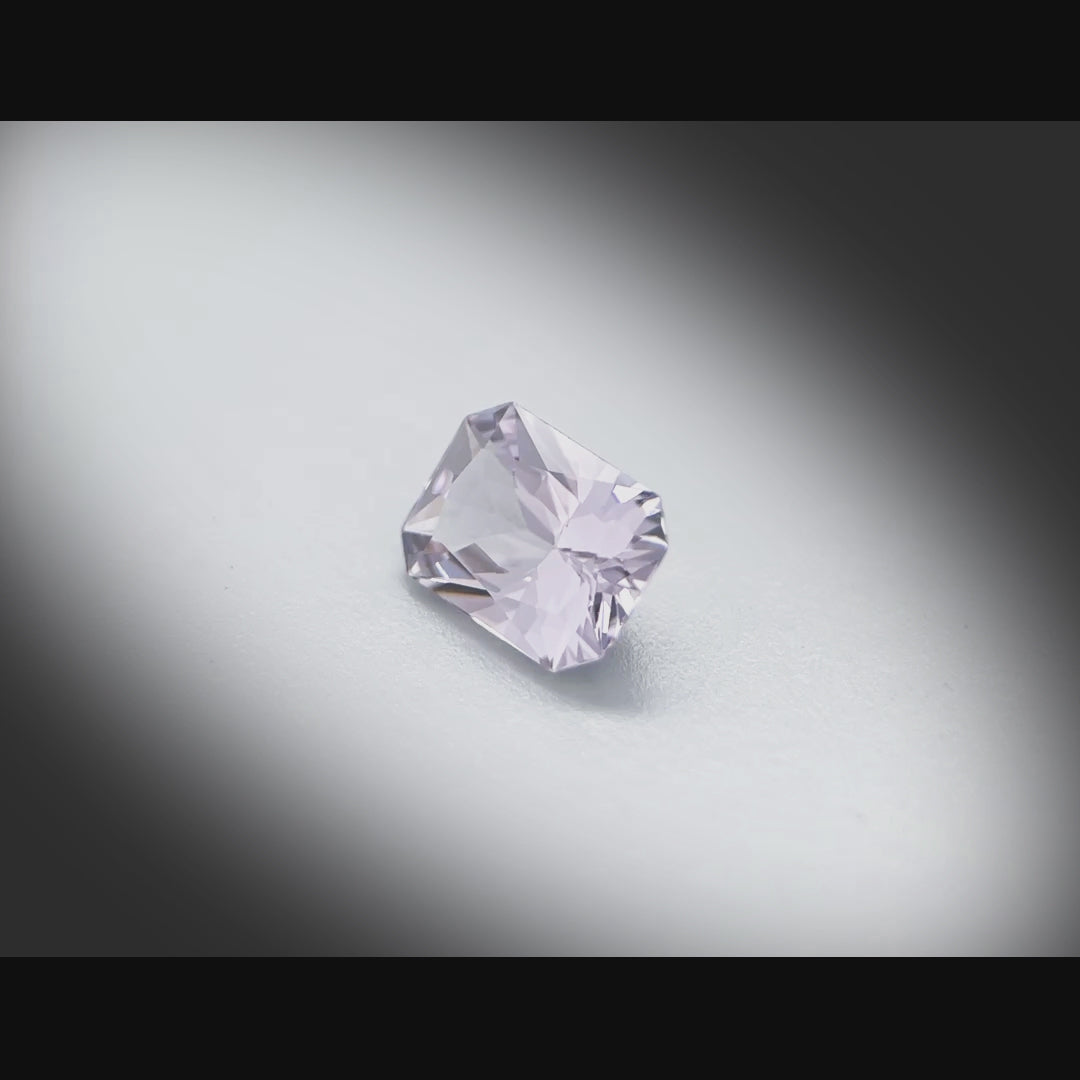 Vidéo d’un spinelle naturel gris-violet rectangulaire à pans coupés de 1.39 ct, facetté, originaire du Sri Lanka, tournant à 360 degrés sur fond gris clair.