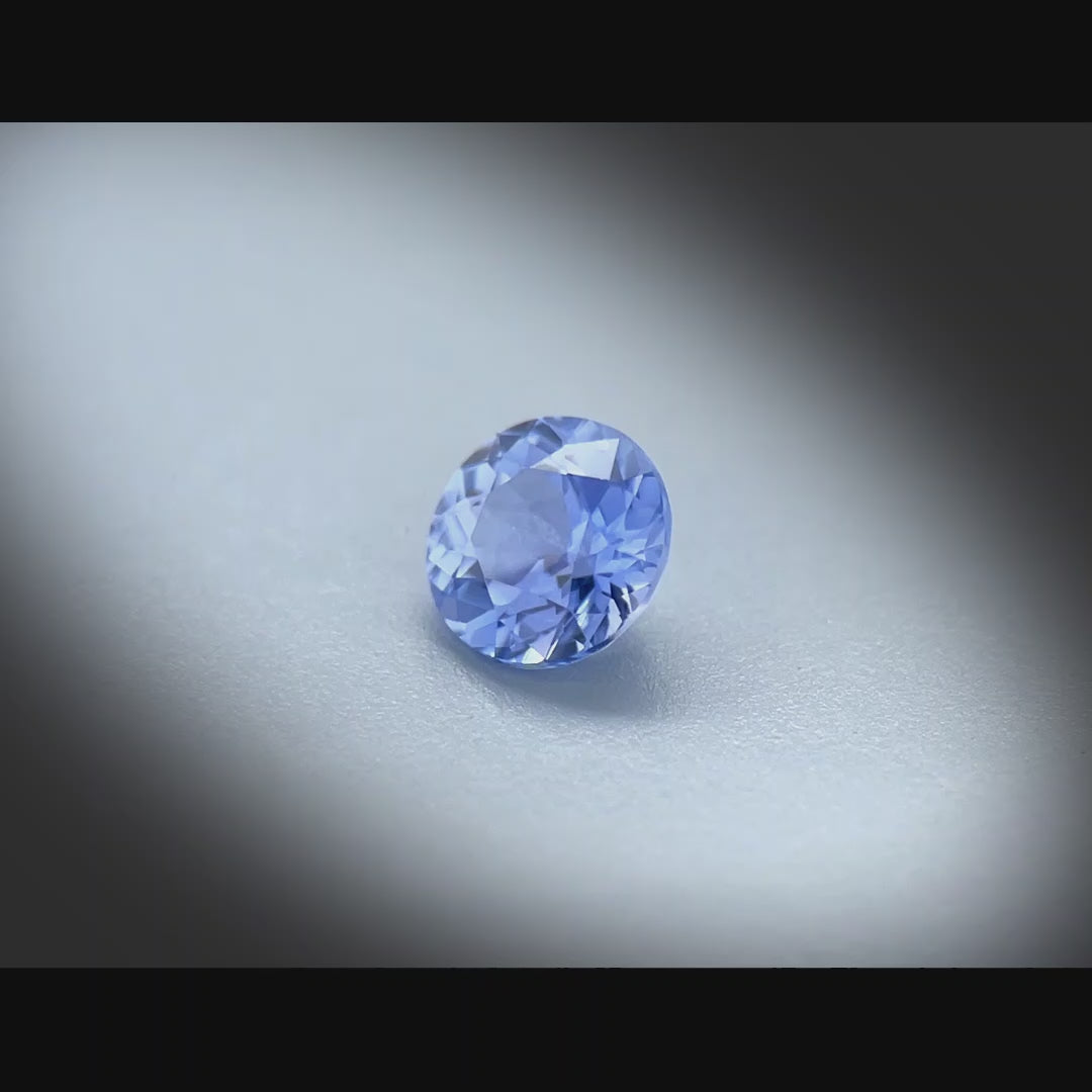 Vidéo d’un saphir bleu-violet naturel non chauffé rond de 0.76ct, originaire du Sri Lanka, tournant à 360 degrés sur un fond gris clair