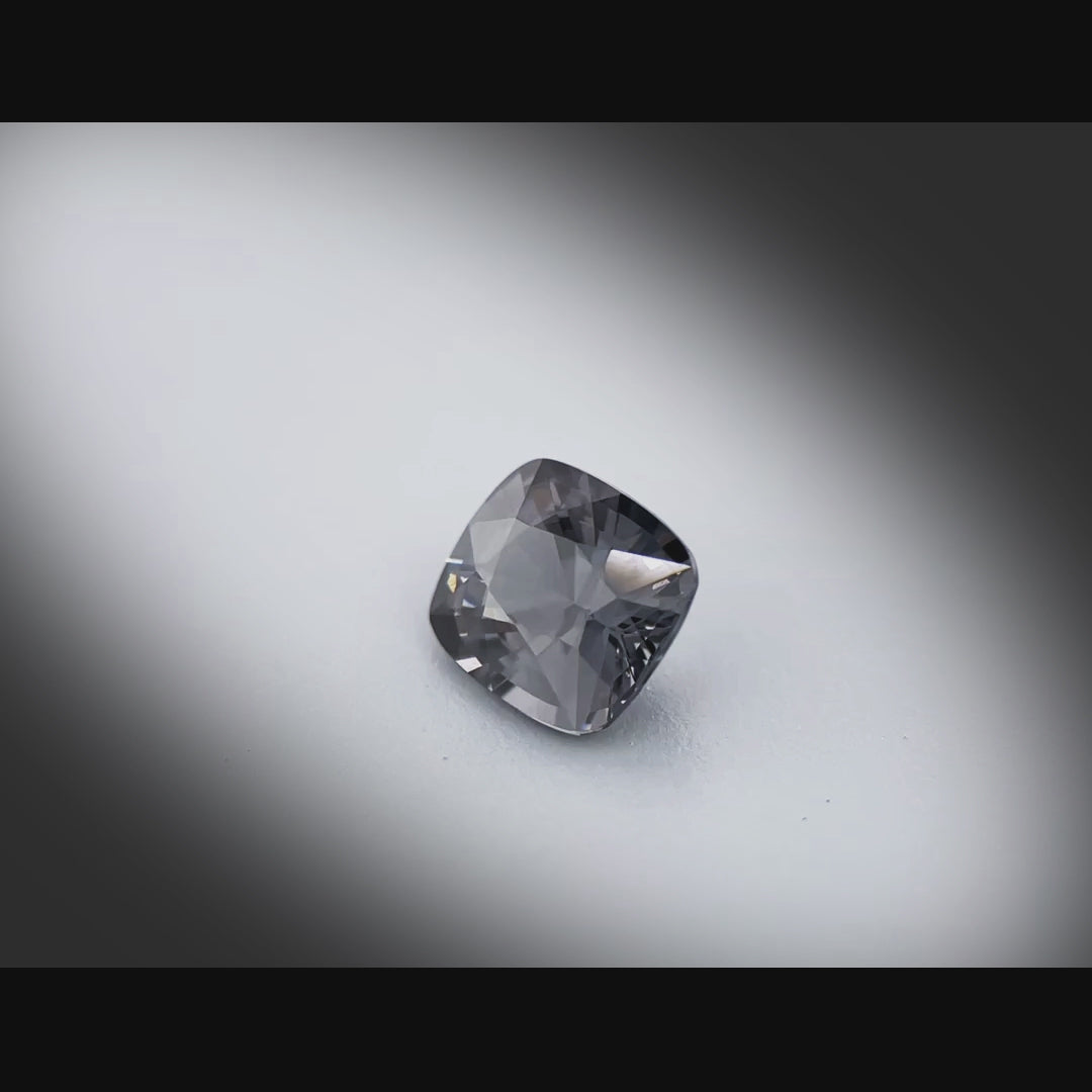 Vidéo d’un spinelle gris naturel coussin facetté de 1.34 ct, originaire du Myanmar, de couleur gris soutenu, tournant à 360 degrés sur fond gris clair