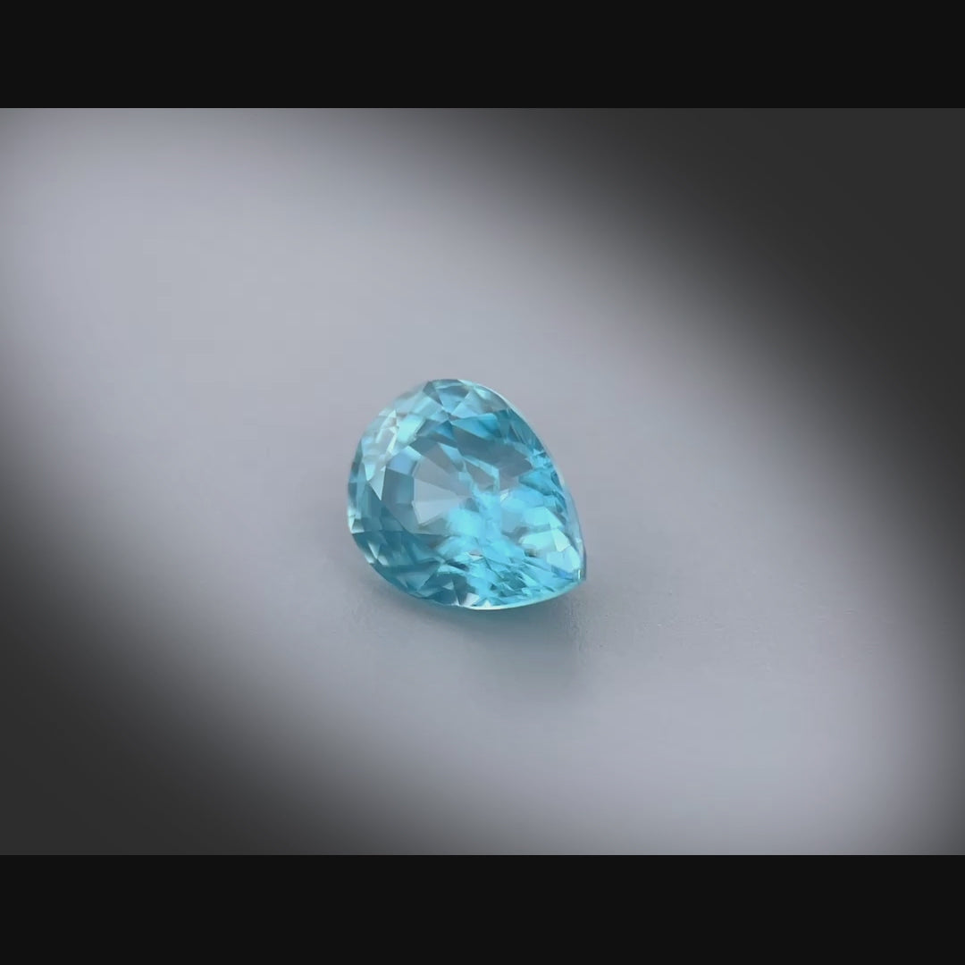 Vidéo d’un zircon naturel bleu en forme de poire de 3.13 ct, originaire du Cambodge, facetté et sans inclusion visible, tournant à 360 degrés sur fond gris clair.