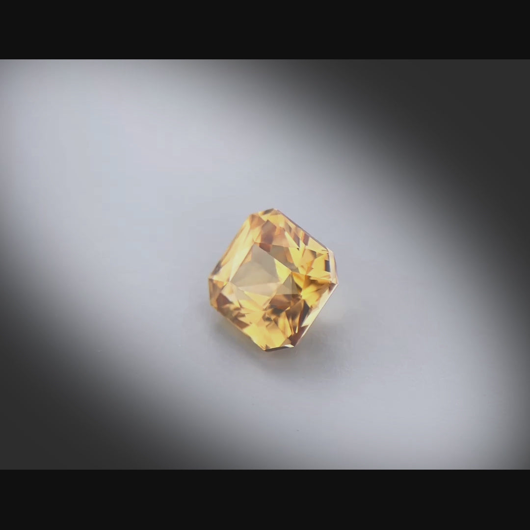 Vidéo d’un zircon jaune-brun naturel facetté de 4.96 ct, originaire de Madagascar, taille rectangle à pans coupés, tournant à 360 degrés sur fond gris clair