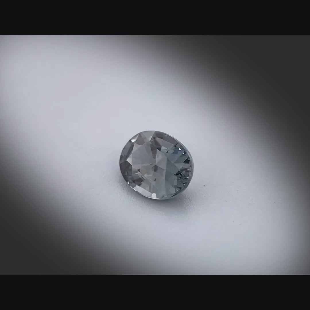 Vidéo d’un spinelle gris naturel ovale facetté de 1.03 ct, originaire du Myanmar, de couleur gris soutenu, tournant à 360 degrés sur fond gris clair