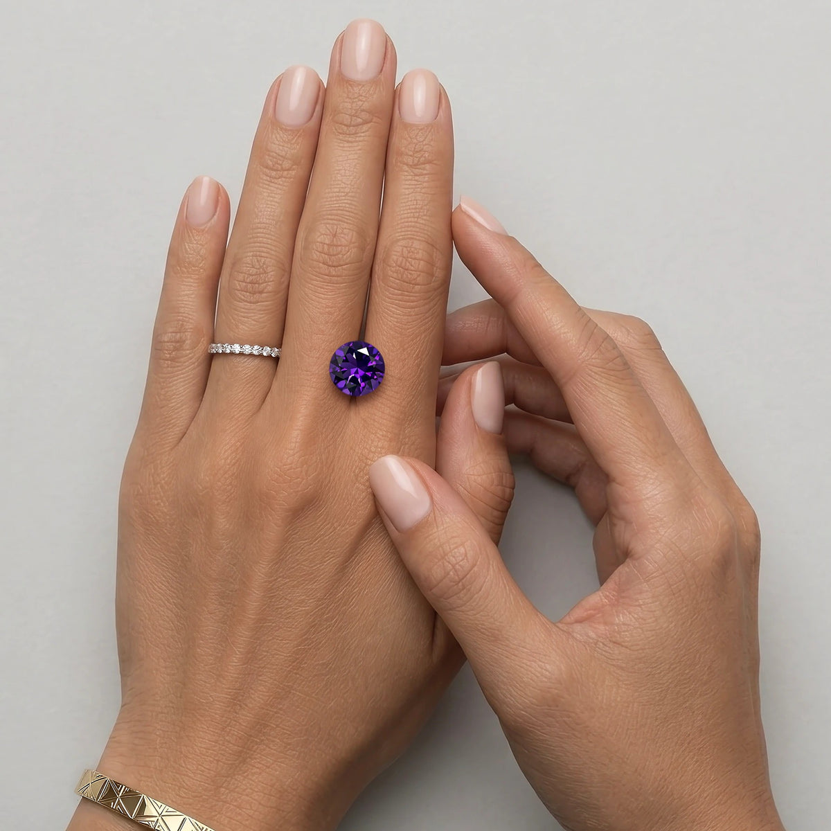 Améthyste non sertie de 3,53 carats mesurant 10,8 sur 10,7 mm, présentée sur une main à taille réelle