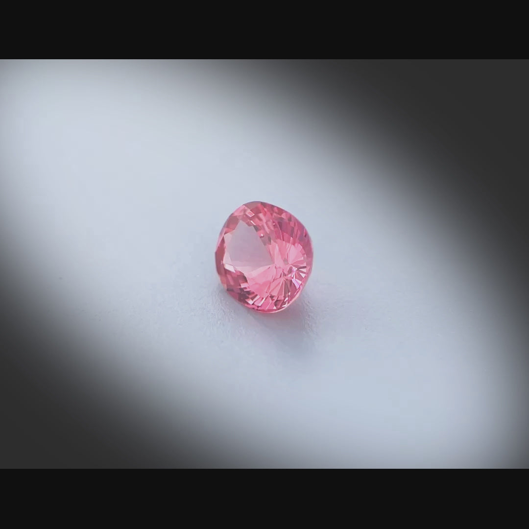 Vidéo d’un spinelle naturel rose-orangé ovale de 0.75 ct, facetté et sans inclusion visible, originaire du Vietnam, tournant à 360 degrés sur fond gris clair.