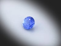 Vidéo d’un saphir bleu naturel rond facetté de 1.06 ct, originaire du Sri Lanka, de couleur bleu soutenu avec une texture laiteuse, tournant sur un fond gris clair.