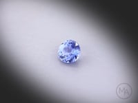 Vidéo d’un saphir bleu rond facetté de 0.44 ct, originaire du Sri Lanka, de couleur bleu prononcé, chauffe traditionnelle,  pierre tournant sur un fond gris clair.