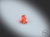 Vidéo d’un grenat spessartite naturel trillion facetté de 1.20 ct, originaire du Nigéria, de couleur orange soutenu, tournant sur un fond gris clair.