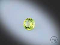 Vidéo d’un péridot naturel rond facetté de 1.12 ct, originaire du Myanmar, de couleur vert-jaune prononcé, tournant à 360 degrés sur un fond gris clair. Traitement: Aucun
