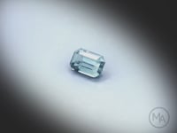 Vidéo d’un saphir teal naturel rectangle à pans coupés facetté de 1.38 ct, originaire du Montana aux États-Unis, de couleur bleu-vert prononcé, tournant sur un fond gris clair.