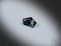 Vidéo d’un saphir bicolore naturel abstrait facetté de 1.61 ct, originaire d’Australie, aux couleurs bleu-vert et jaune, tournant avec élégance sur un fond gris clair.