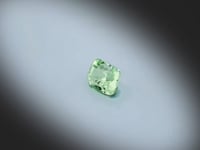 Vidéo d’un grenat menthe naturel coussin rectangle facetté de 1.01 ct, originaire de Merelani en Tanzanie, de couleur vert-jaune prononcée, tournant à 360 degrés sur un fond gris clair.