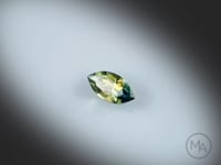 Vidéo d’un saphir bicolore naturel navette facetté de 0.57 ct, originaire d’Australie, présentant une association naturelle de jaune et de bleu-vert, gemme sur un fond gris clair.