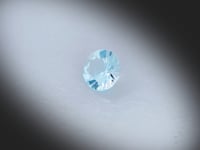 Vidéo d’une topaze bleue naturelle Sky Blue ronde facettée de 1.81 ct, originaire du Brésil, de couleur cyan-bleuté très léger, pierre tournant sur un fond gris clair.
