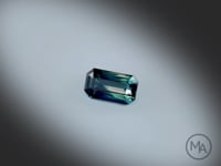Vidéo d'un saphir bicolore naturel de 1,80 carat, facetté, aux teintes profondes et sans traitement. Origine: Australie. Rotation lente sur fond gris