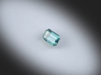 Vidéo d’un Saphir Teal naturel rectangle à pans coupés facetté de 0.81 ct, originaire d’Australie, de couleur cyan-vert profond, pierre précieuse tournant sur un fond gris clair.